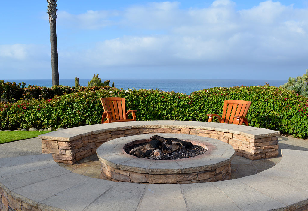 Stone fire pit with two adirondack chairs.